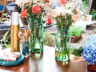 Peach and coral carnations arranged in seafoam green glass vases